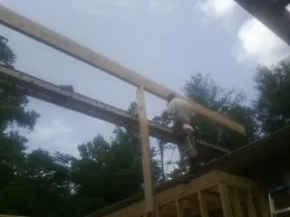 Carpenter setting a ridge beam over a new addition frame — Ice Dam Removal by Roofing Brothers in Fair Oaks