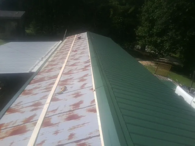 Old rusted panels beside newly installed green metal roofing — Wind Damage Roof Repair by Roofing Brothers in Fair Oaks