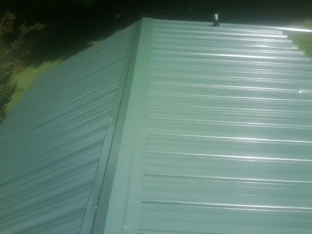 New green metal panels meeting at the ridge of a roof — Flat Roof Repair work by our crew in Fair Oaks