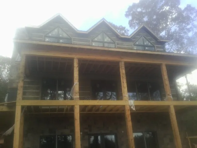 Dormers and porch framing on a large log home under construction — Roof Coating work by our crew in Fair Oaks