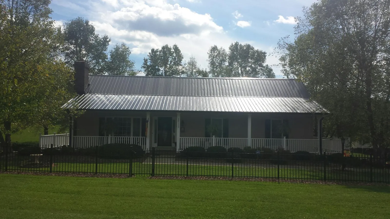 Gray metal roof on a brick ranch with a full width front porch — Gutter Guard Installation work by our crew in Fair Oaks