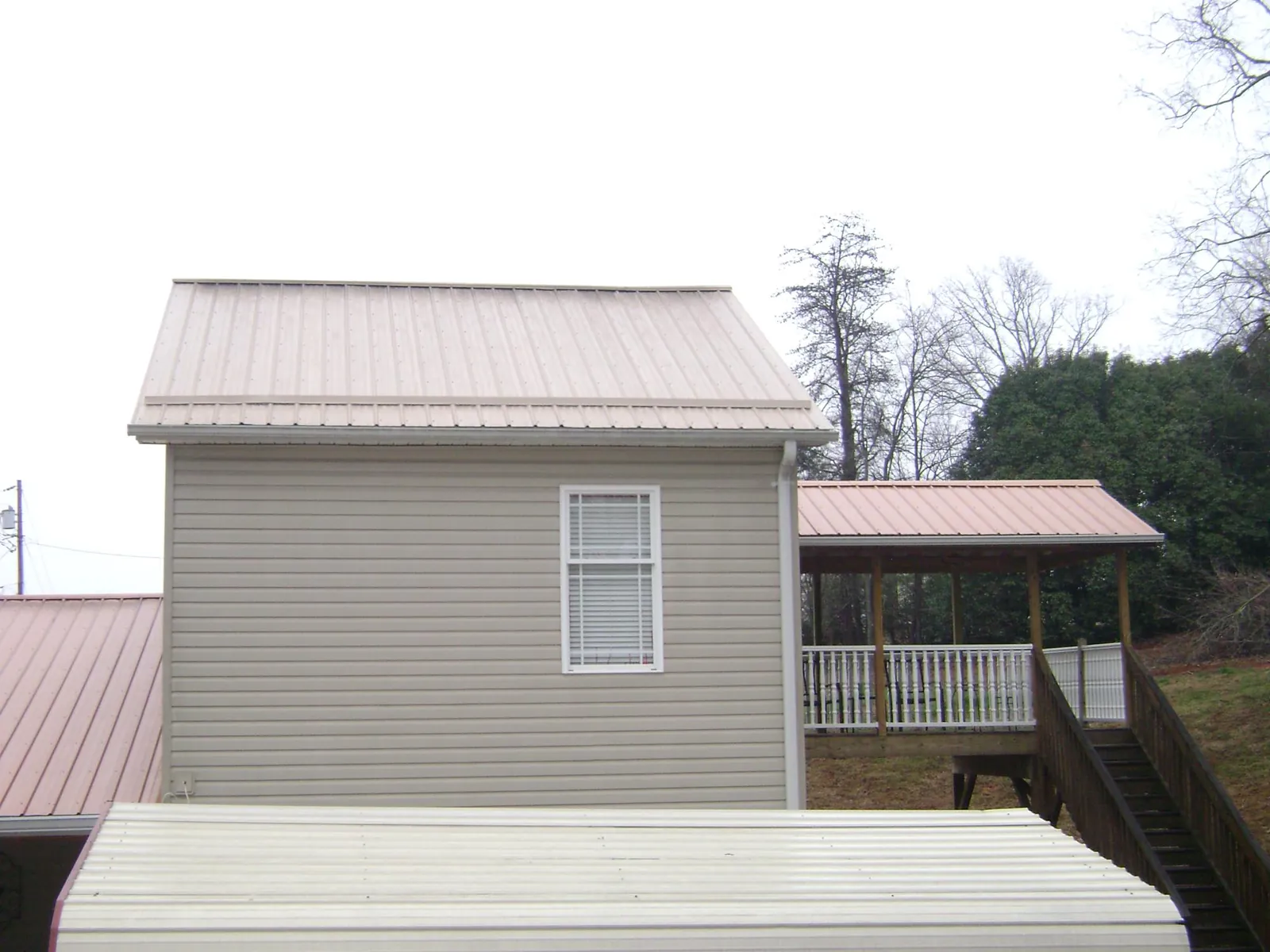 Tan metal roofs on a two story addition and attached porch, from a Roof Replacement job in Fair Oaks